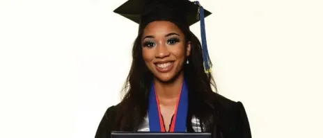 A smiling women holding a diploma from Mount Mercy University.